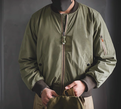 Model wearing army green MA-1 flight jacket with ribbed collar and zip sleeve pocket.