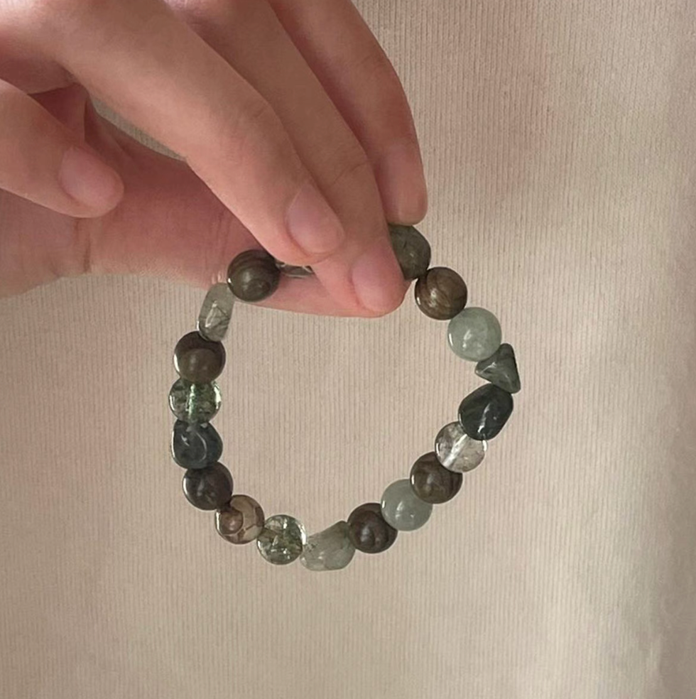 forest spirit gemstone bracelet in green rutilated quartz green serpentine and dzi beads held in hand