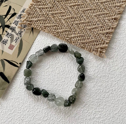 forest spirit gemstone bracelet in green rutilated quartz displayed flat on textured background