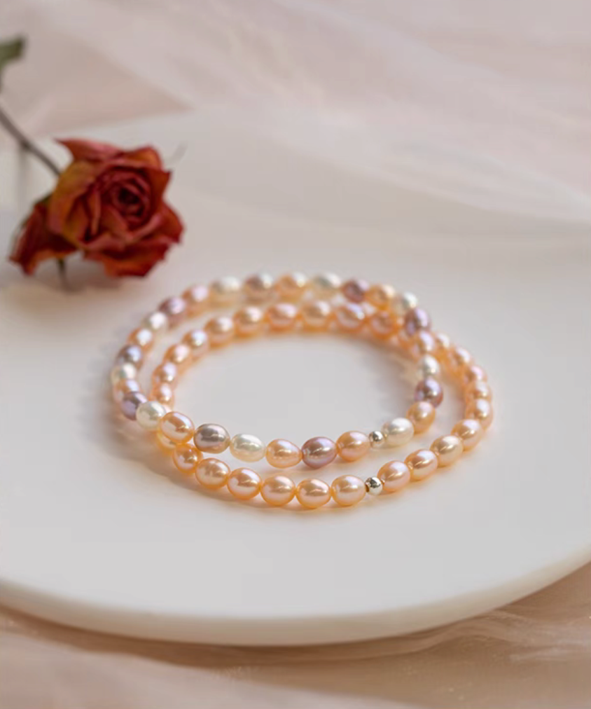 Stacked display of peachy pink freshwater pearl stretch bracelets layered together for a bold elegant styling look.