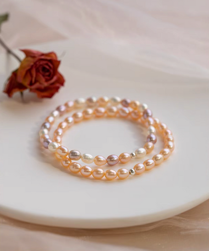 Stacked display of peachy pink freshwater pearl stretch bracelets layered together for a bold elegant styling look.