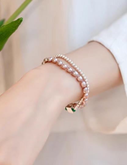Wrist shot showing layered styling of white with pinkish purple freshwater pearl bracelets for a modern stacked look.
