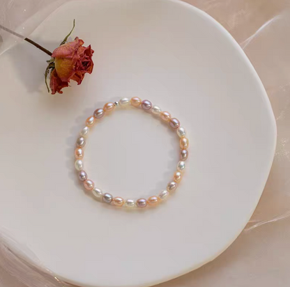 Flat lay of white with pinkish purple mixed freshwater pearl bracelet on plate, showcasing multi-tone elegance.