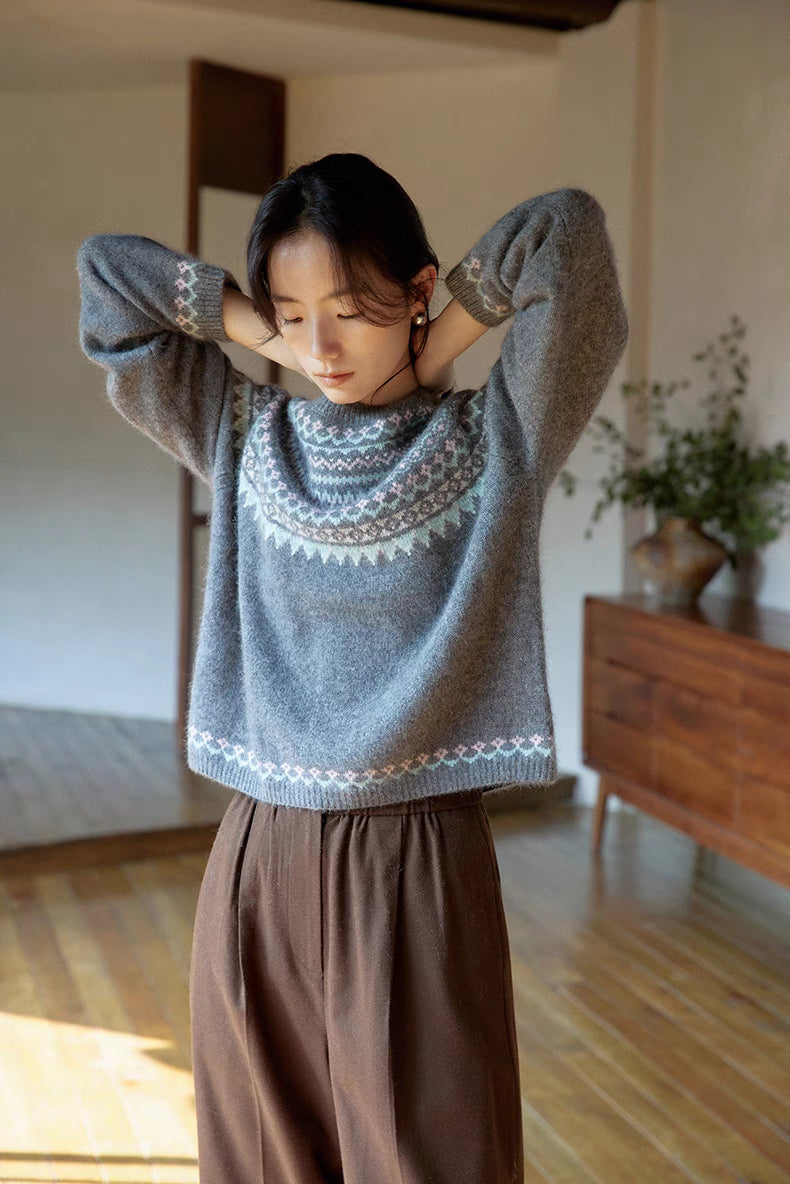 Model wearing pine gray Frosted Peaks Fair Isle Sweater raising arms showing soft knit texture and intricate Fair Isle pattern