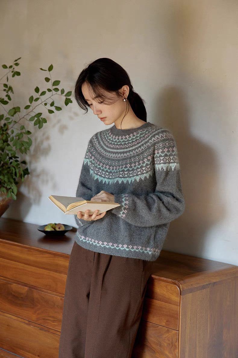 Model in pine gray Frosted Peaks Fair Isle Sweater reading book indoors showcasing relaxed silhouette and soft wool blend