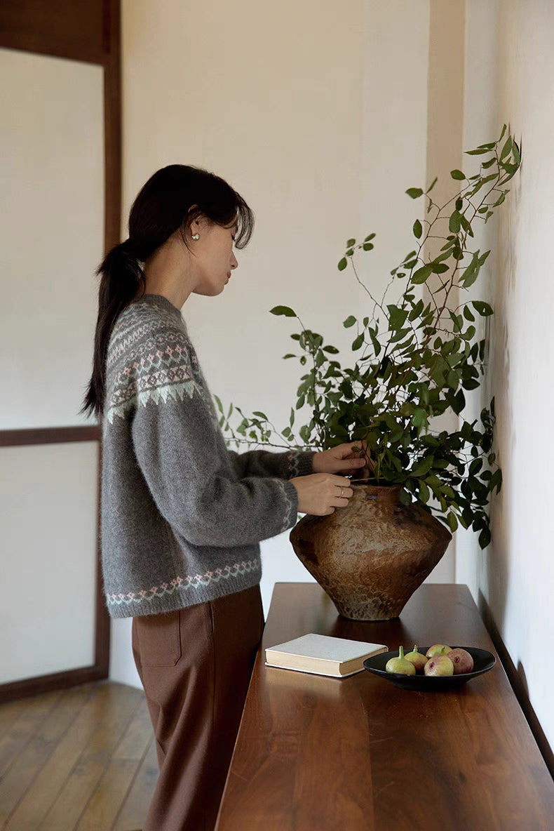 Side view of model in pine gray Frosted Peaks Fair Isle Sweater adjusting plant showcasing sleeve detail and soft blended knit texture