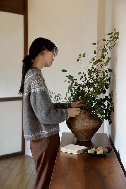 Side view of model in pine gray Frosted Peaks Fair Isle Sweater adjusting plant showcasing sleeve detail and soft blended knit texture