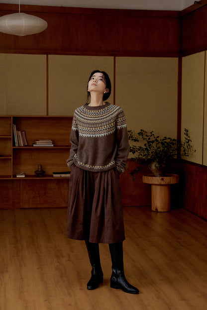 Model wearing smoky brown Frosted Peaks Fair Isle Sweater full body standing in wooden interior showcasing relaxed fit and Nordic pattern styling