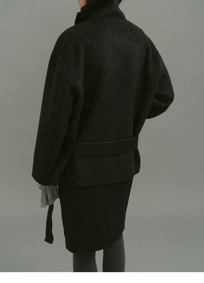 Back view of charcoal wool coat with self-fabric belt and dropped shoulders