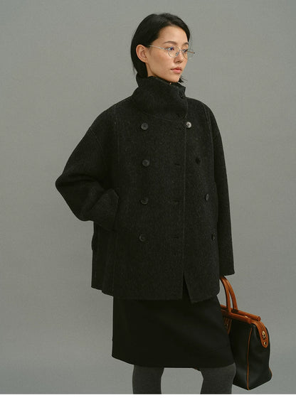 Charcoal double-breasted wool coat worn without belt, showing straight H-line cut