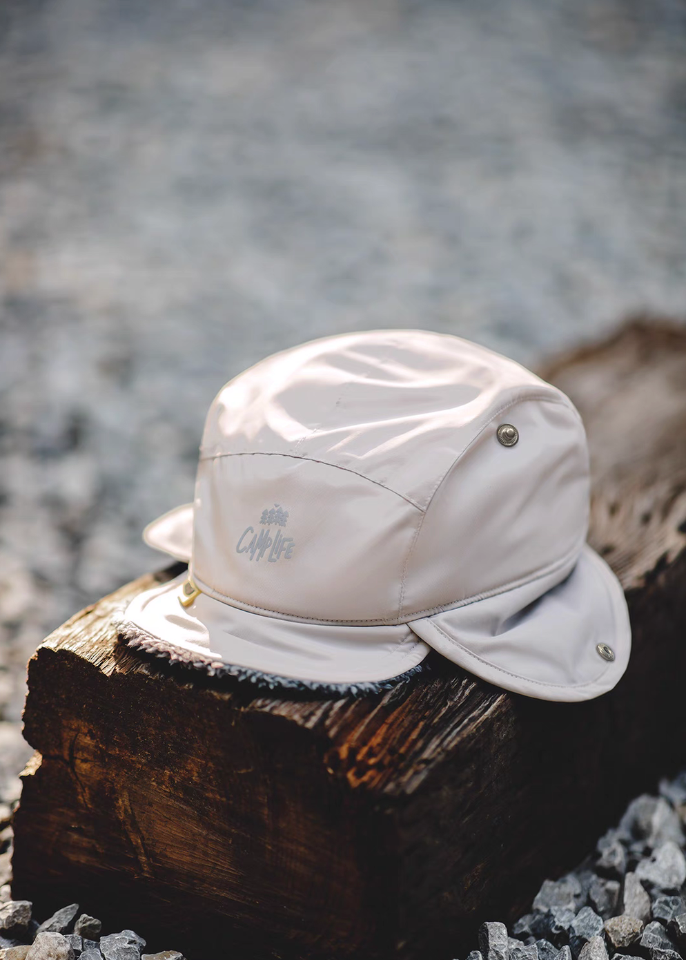 Glacier Guard Fleece Cap in mountain rock gray and white front view placed on wood outdoors showing water-resistant fabric short flat brim and clean modern design