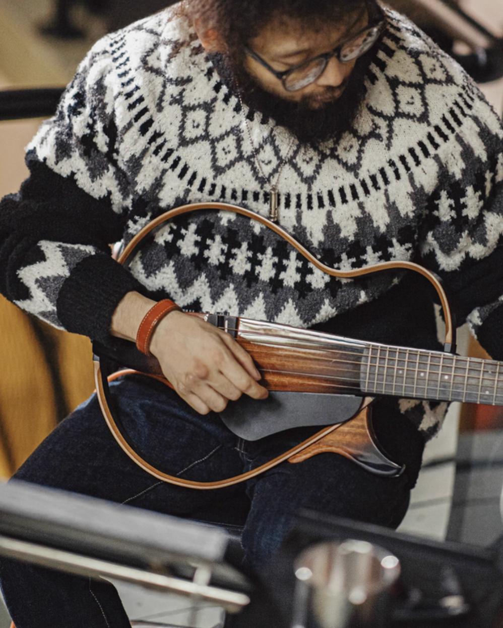 Man wearing Glacier Peaks Knit Sweater Black White Gray while playing guitar showing cozy knit texture relaxed fit and winter-ready styling