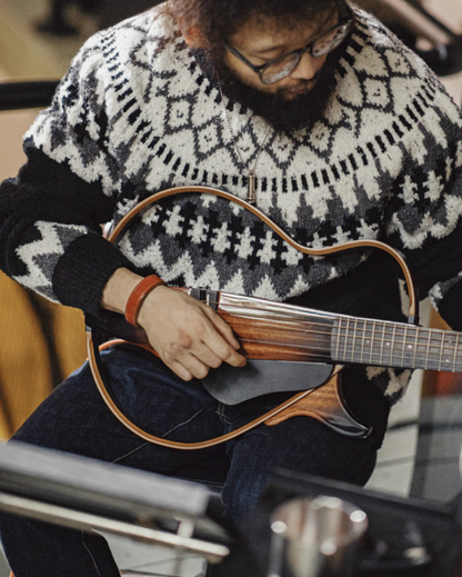 Man wearing Glacier Peaks Knit Sweater Black White Gray while playing guitar showing cozy knit texture relaxed fit and winter-ready styling