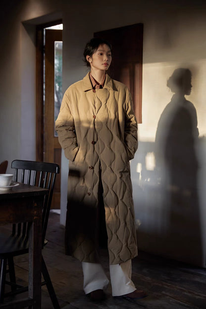 Model wearing Gourd Stitch Longline Coat in khaki full body front view with warm lighting highlighting quilted texture and longline silhouette