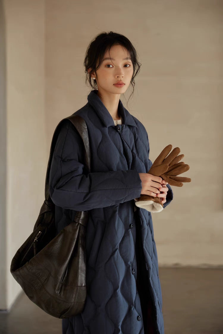 Close-up of navy blue Gourd Stitch Longline Coat showing quilted texture, collar detail, and styling with leather shoulder bag and gloves