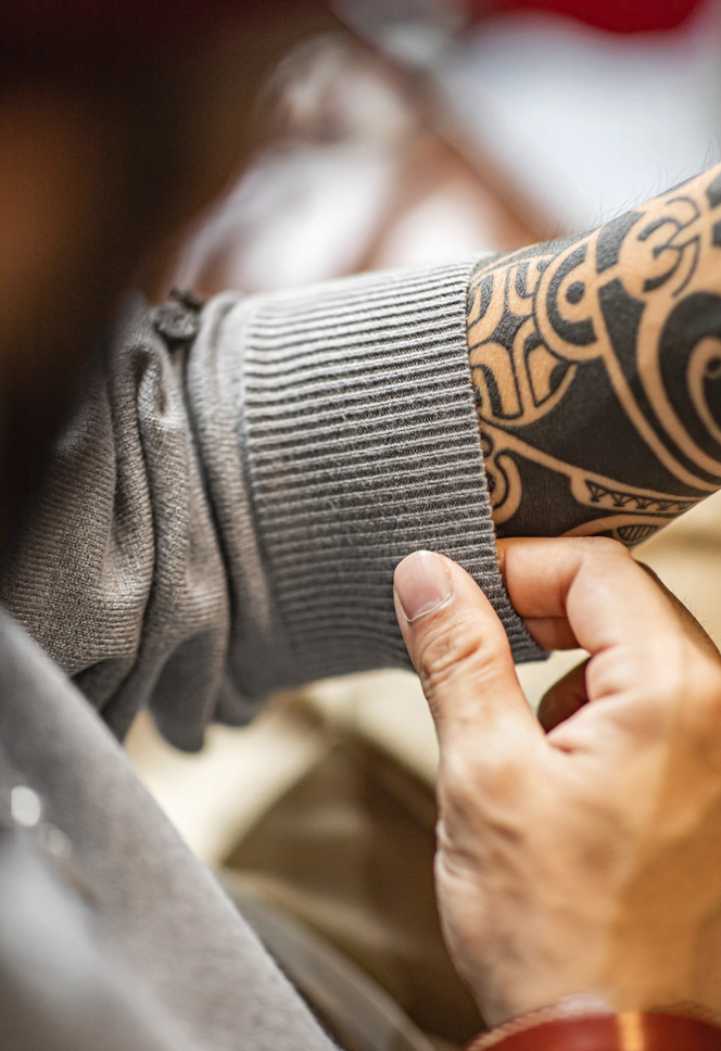 Close-up of ribbed cuff and sleeve texture on gray knit polo sweater.