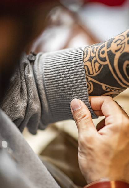 Close-up of ribbed cuff and sleeve texture on gray knit polo sweater.