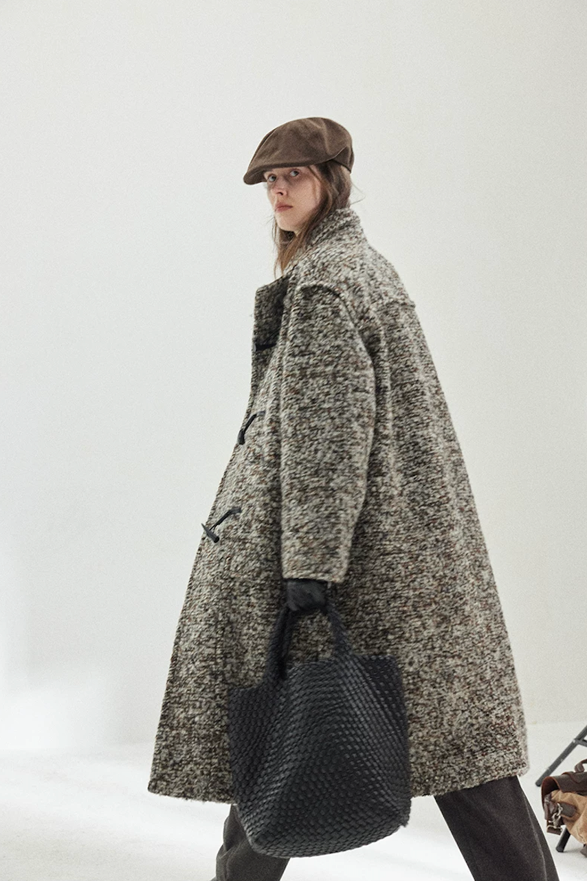 Side view of a Gray Marl long bouclé coat in motion, showing the toggles and dropped shoulders