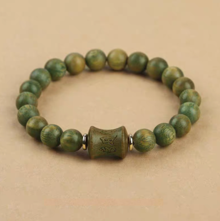 green sandalwood beaded bracelet with carved central bead displayed on neutral background showing full circular design