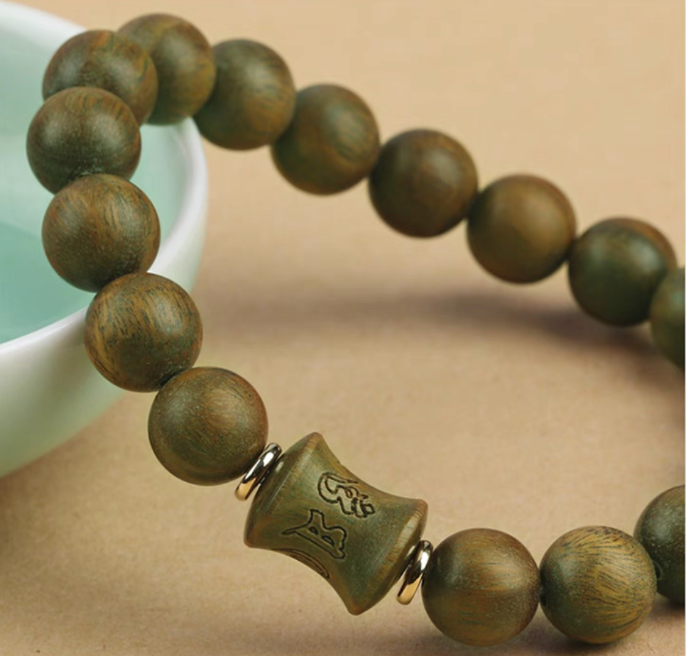 close-up of green sandalwood bracelet highlighting carved central bead and smooth round wood beads