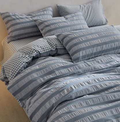 Slate Blue Grid cotton bedding close-up with textured stripe duvet cover and checked pillow and sheet detail