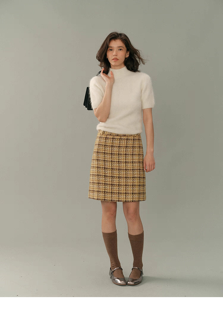 Full-body image of the cream HaloFuzz alpaca turtleneck tee styled with a yellow tweed skirt, brown knee socks, and metallic Mary Jane flats.