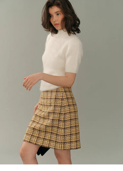Side profile of model wearing the cream alpaca short-sleeve turtleneck tee with a yellow tweed A-line skirt against a soft grey background.