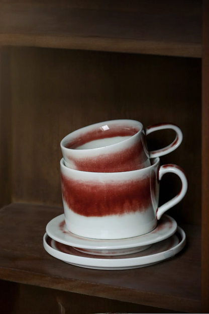 Stacked handcrafted crimson glaze ceramic cups and saucers in beige and red highlighting space-saving storage design