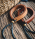 Handcrafted leather loop bracelets in dark brown and original color placed together on wooden surface showing brass beads and blue cord details