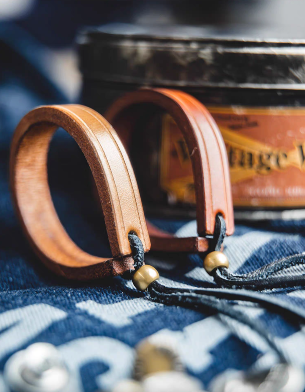 Handcrafted leather loop bracelets in dark brown and original color placed beside leather case showing product texture and craftsmanship