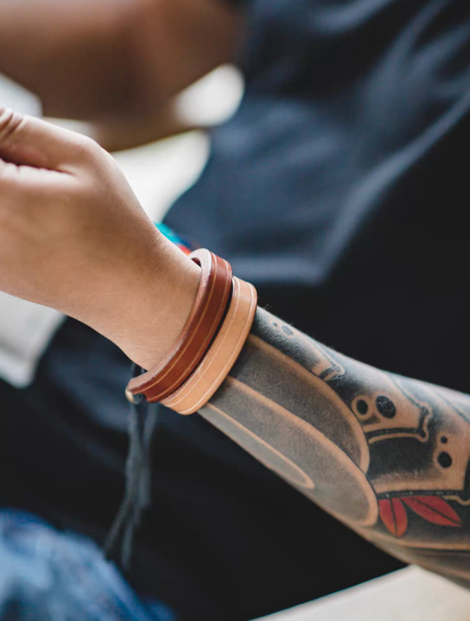 Dark brown and original color handcrafted leather loop bracelets worn stacked on wrist close-up showing layered leather bands