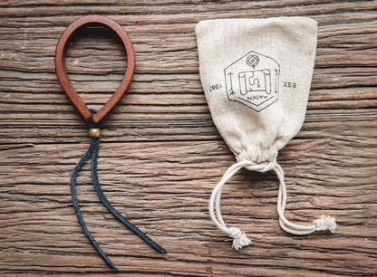 Dark brown handcrafted leather loop bracelet flat lay next to fabric pouch showing single bracelet and adjustable cord