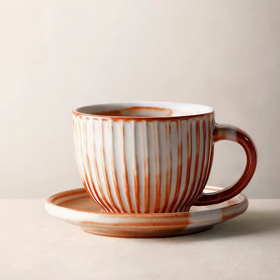 Style 2 striped ceramic cup and saucer in off-white and orange filled with coffee with spoon and table setting