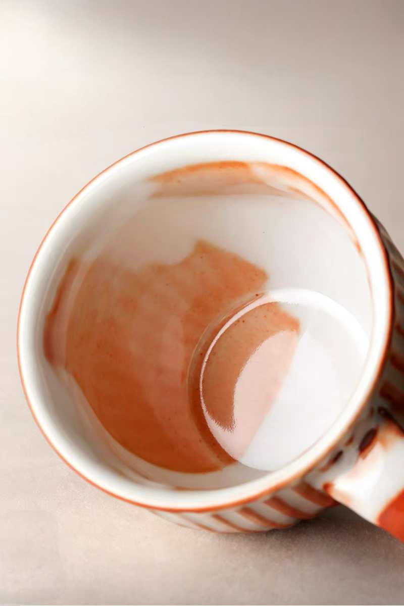 Style 3 ceramic cup and saucer in off-white and orange shown in clean front view with balanced minimalist design