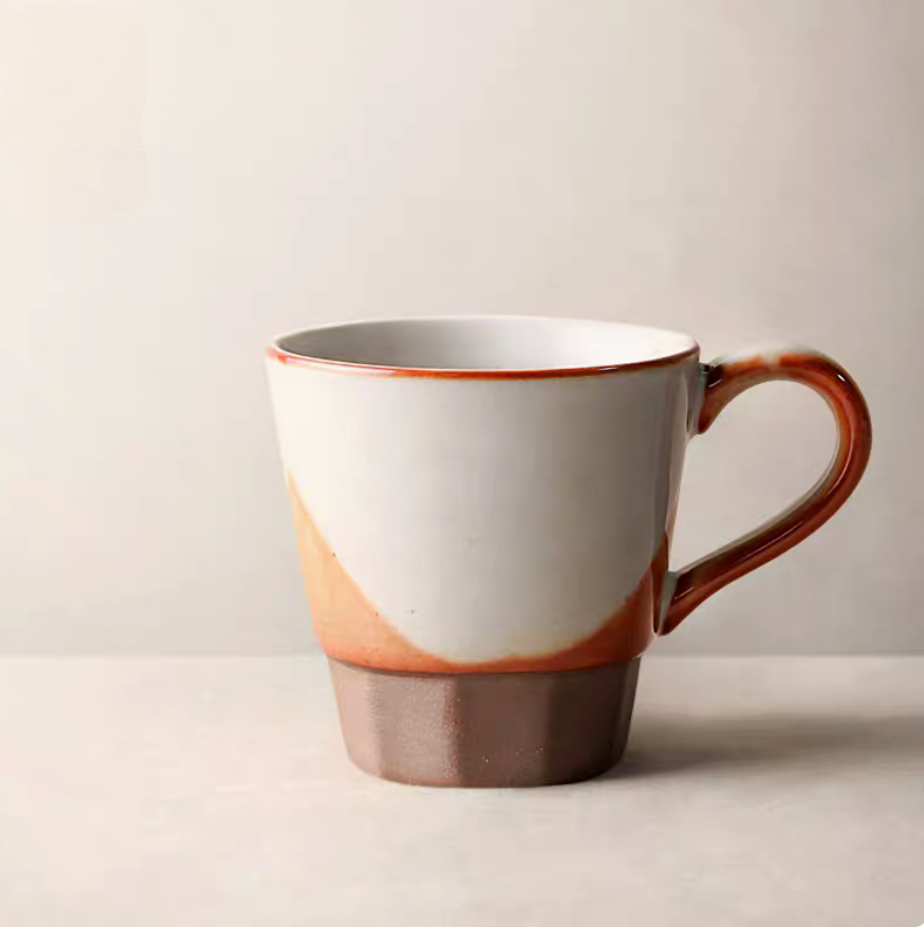 Style 3 handcrafted ceramic cup and saucer in off-white and orange with latte art placed on book in lifestyle setting