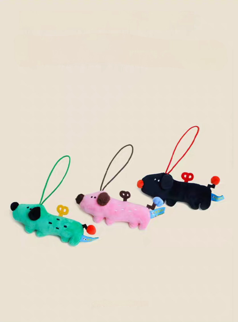 Handmade plush puppy charm keychains in pink green and black shown together with cute wind-up design