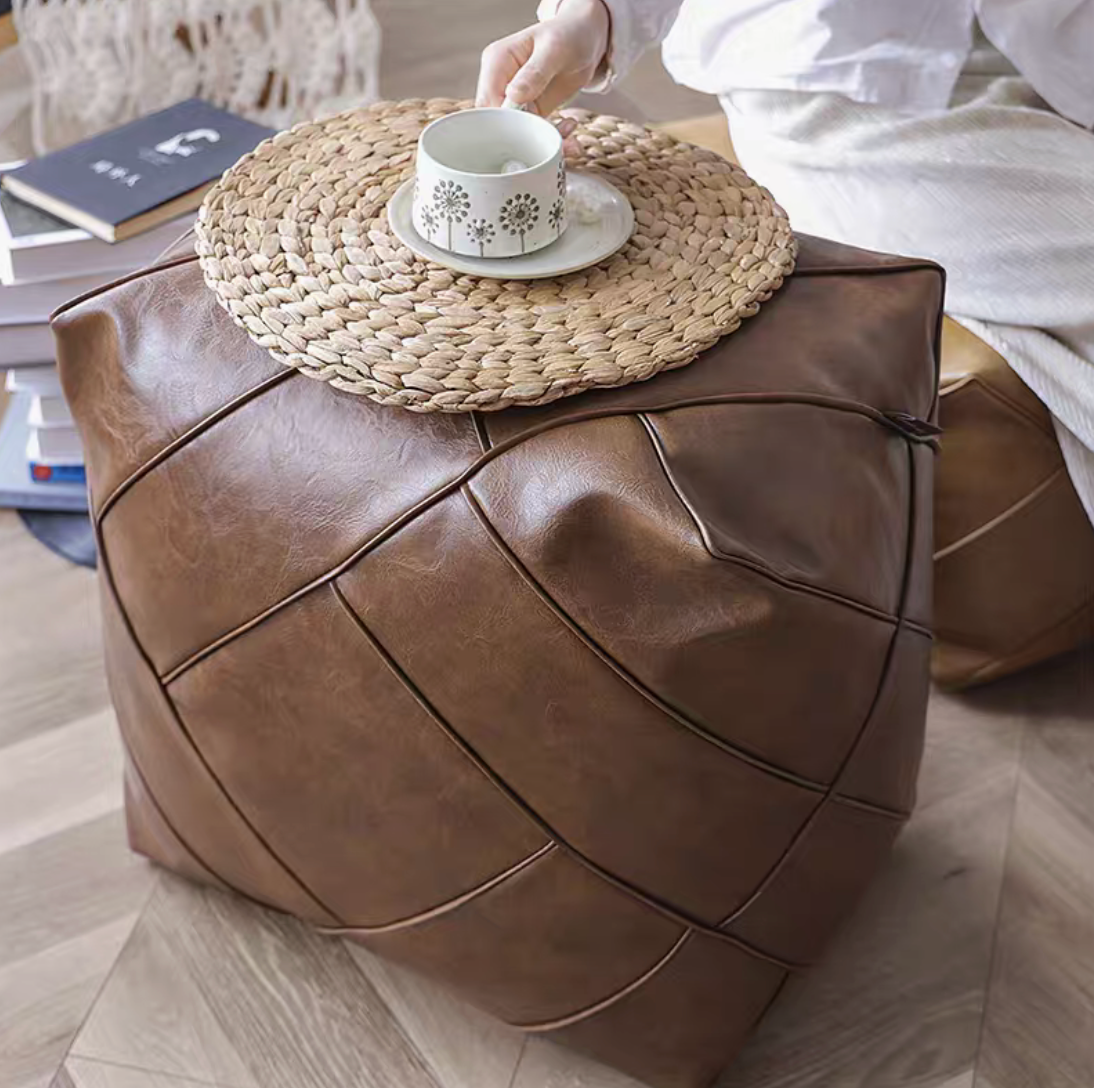 Brown coffee leather cube pouf used as a table with a woven tray and cup placed on top in a home setting