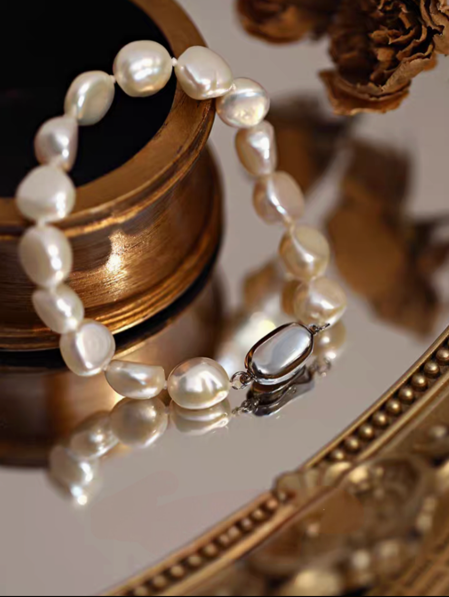 Heavy baroque freshwater pearl bracelet with vintage-style clasp detail displayed on decorative surface with reflective finish