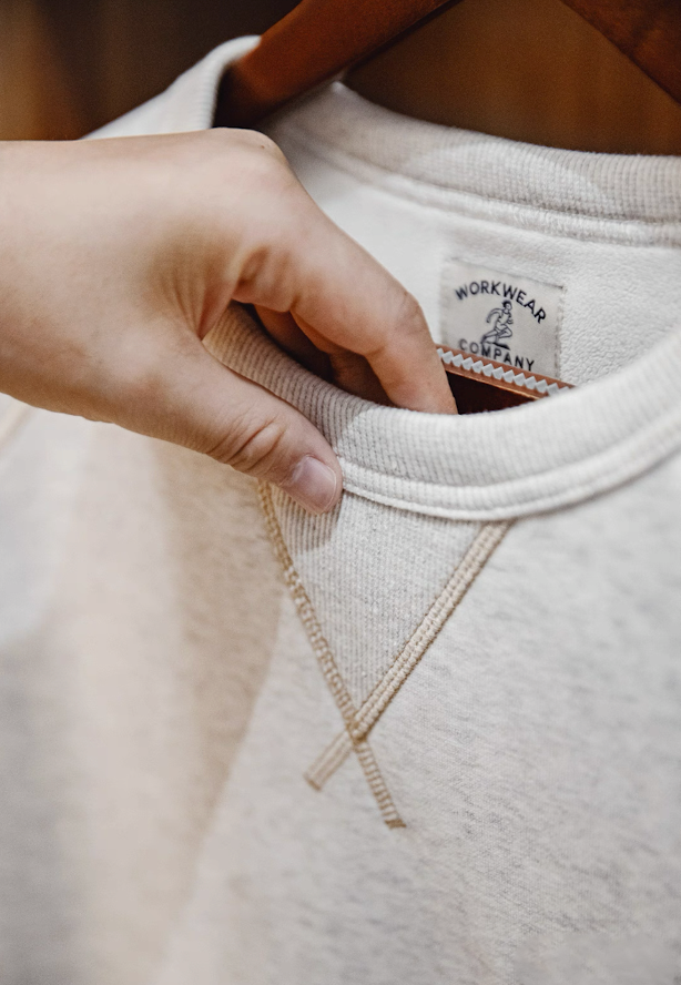 Close-up of V-stitch neck detail and ribbed collar construction on sweatshirt.