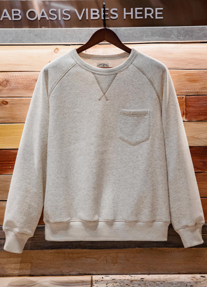 Crewneck sweatshirt hanging on wooden wall background, showing V-stitch collar and relaxed shape.