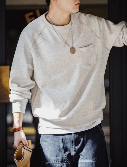 Model walking outdoors wearing gray fleece crewneck with casual accessories.