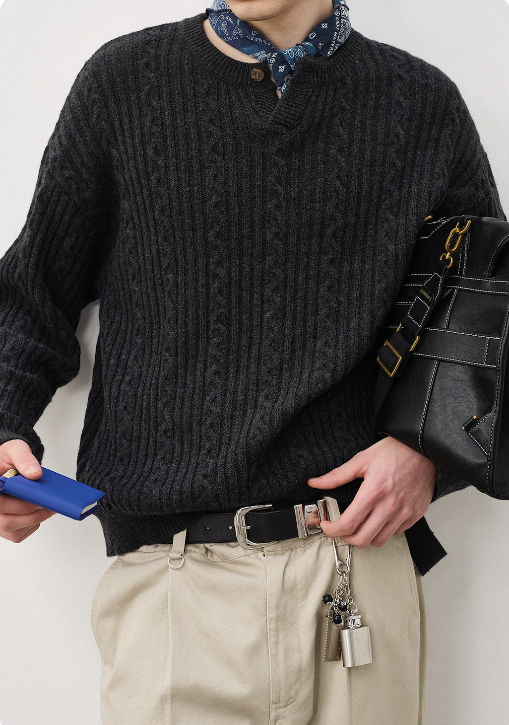 Closeup texture of charcoal cable-knit sweater showing Henley button detail