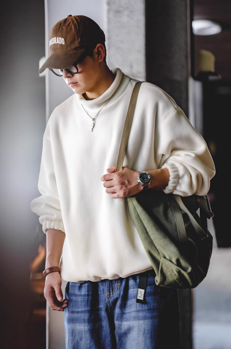 Model wearing Cream White Mock Neck Sweatshirt side view carrying green bag