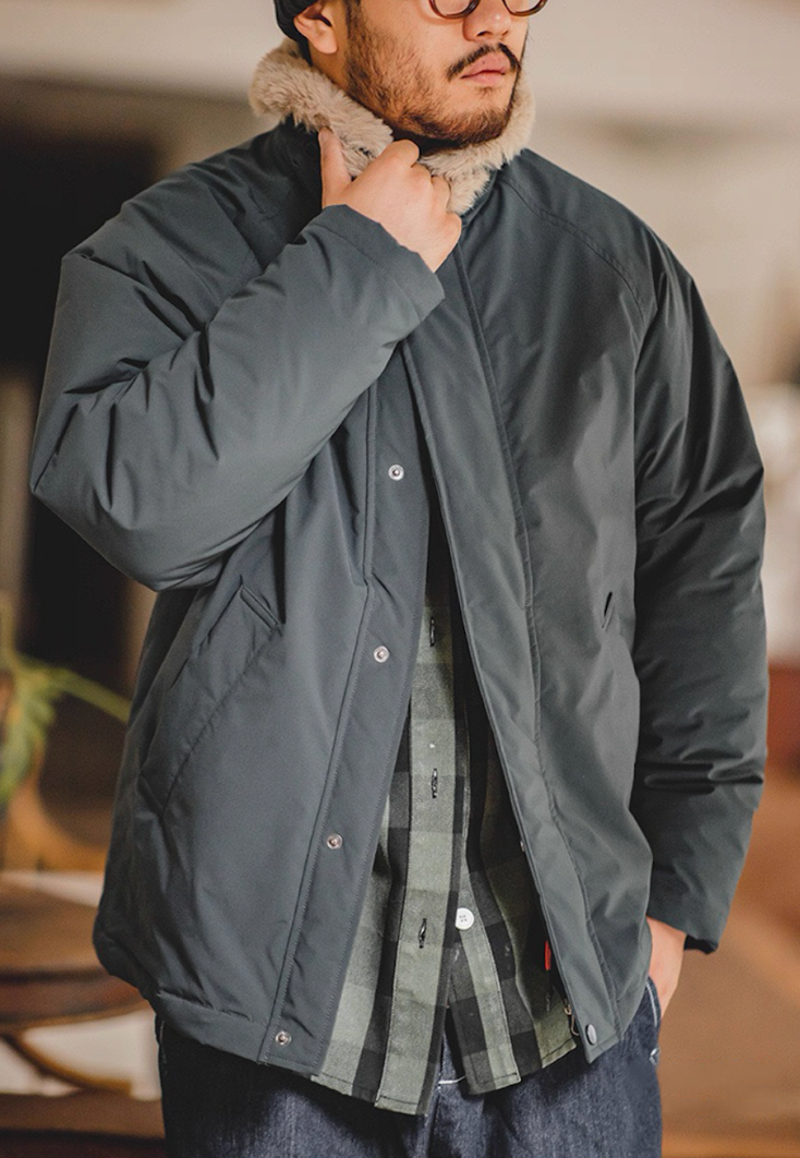 Close-up of man adjusting faux-fur collar on blue bomber jacket.