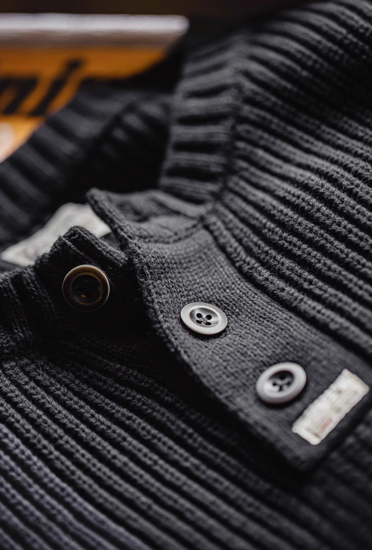 Close-up of black Henley sweater buttons and knit details.