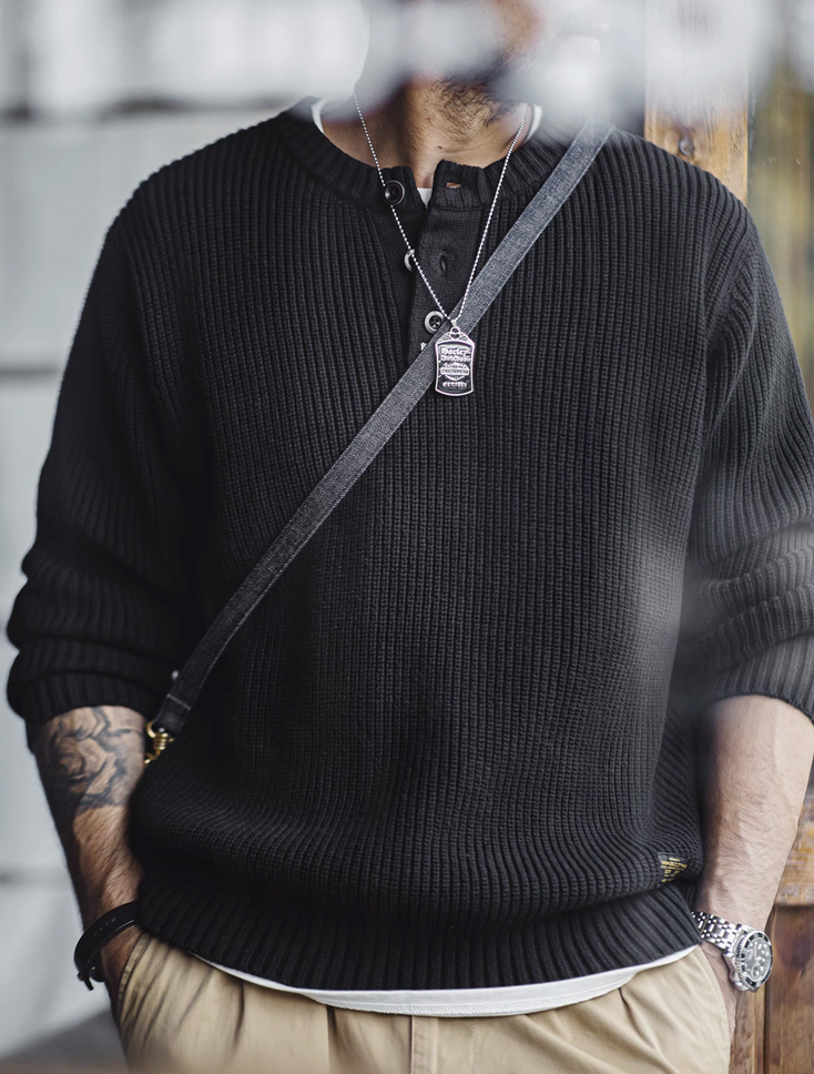 Model wearing ribbed black Henley sweater with casual khaki pants.
