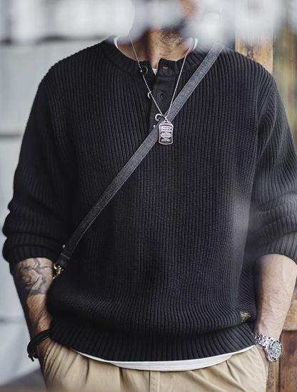 Model wearing ribbed black Henley sweater with casual khaki pants.