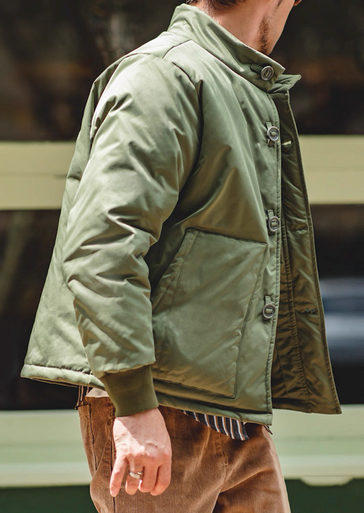 Side angle showing oversized buttons and pocket on army green jacket.