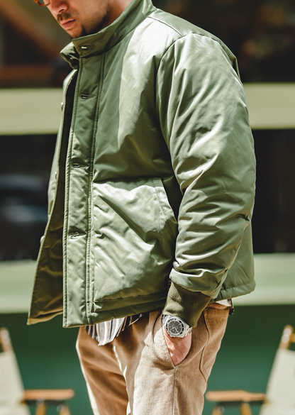 Model in army green padded jacket, side view with tall stand collar.