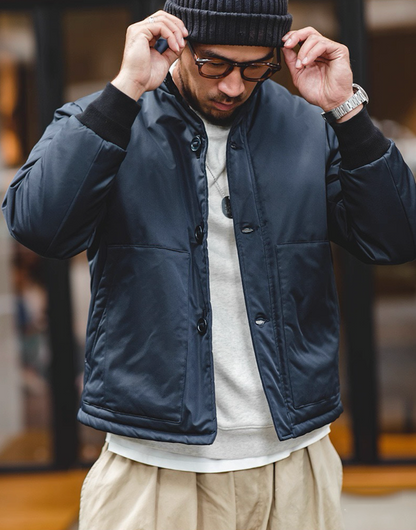 Model wearing navy padded bomber jacket, front view with pockets.